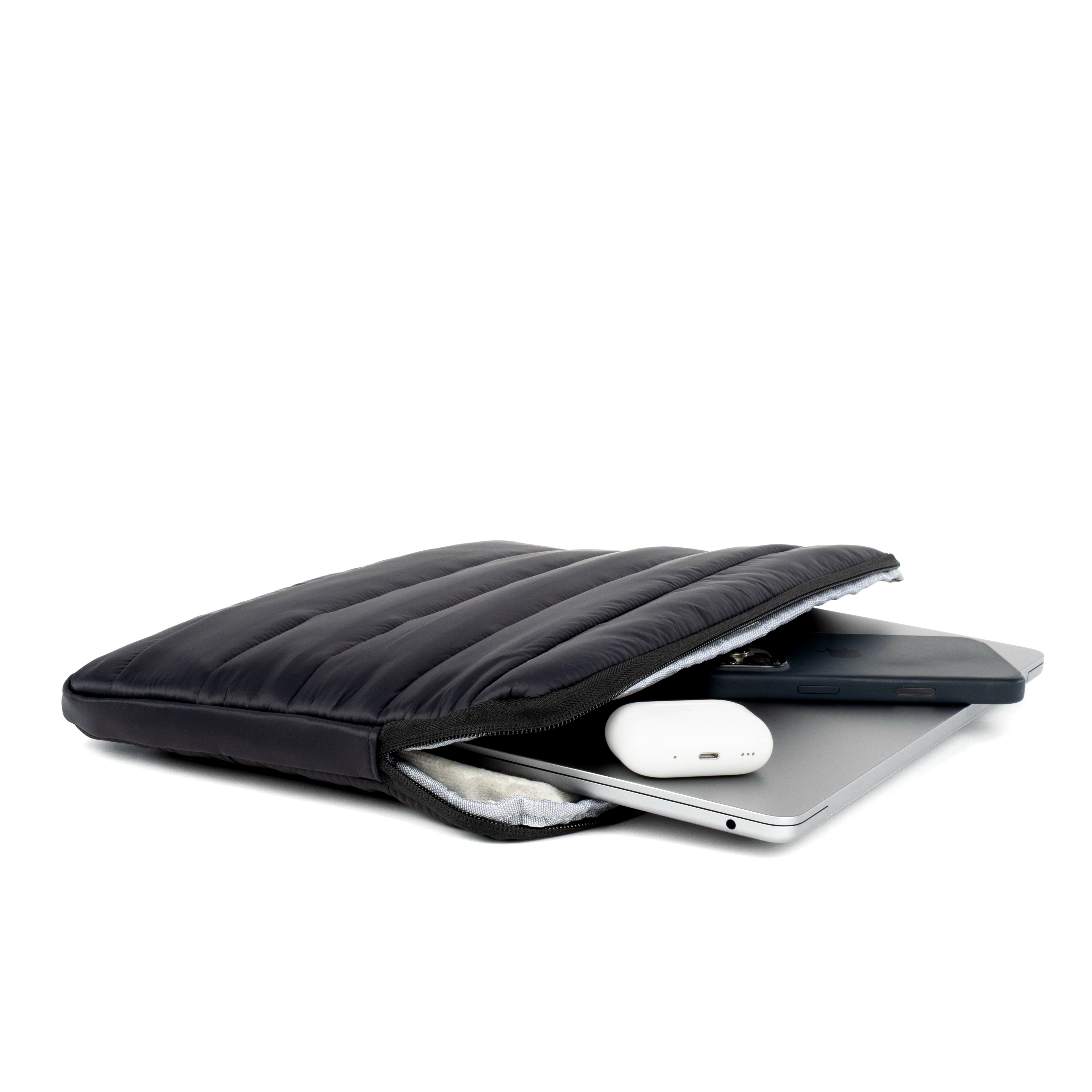 Black Humley padded laptop sleeve holding a MacBook, phone, and wireless earbuds – open to show storage capacity