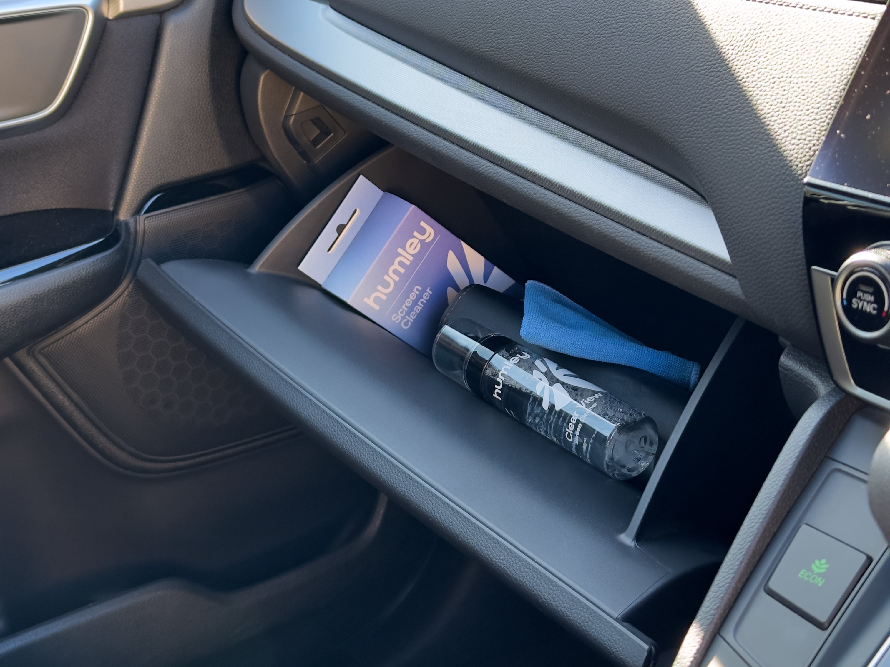 Humley Clear View Screen Cleaner, packaging, and cloth neatly stored in a car glovebox.